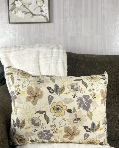 Handmade floral beige throw pillow sitting on brown sofa with white blanket