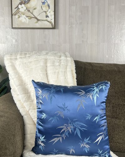 Handmade blue pillow with silver sitting on white blanket