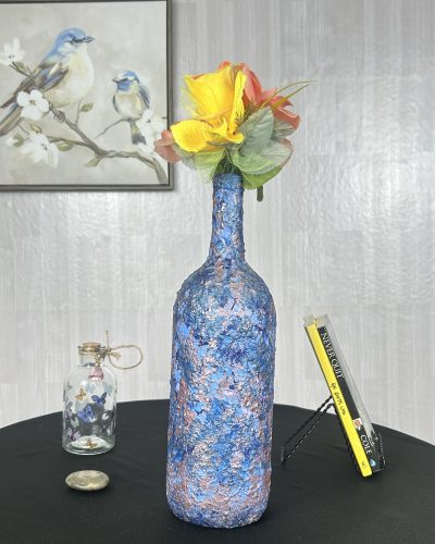 Hand painted blue swirl vase with traces of purple and a flower bouquet inside