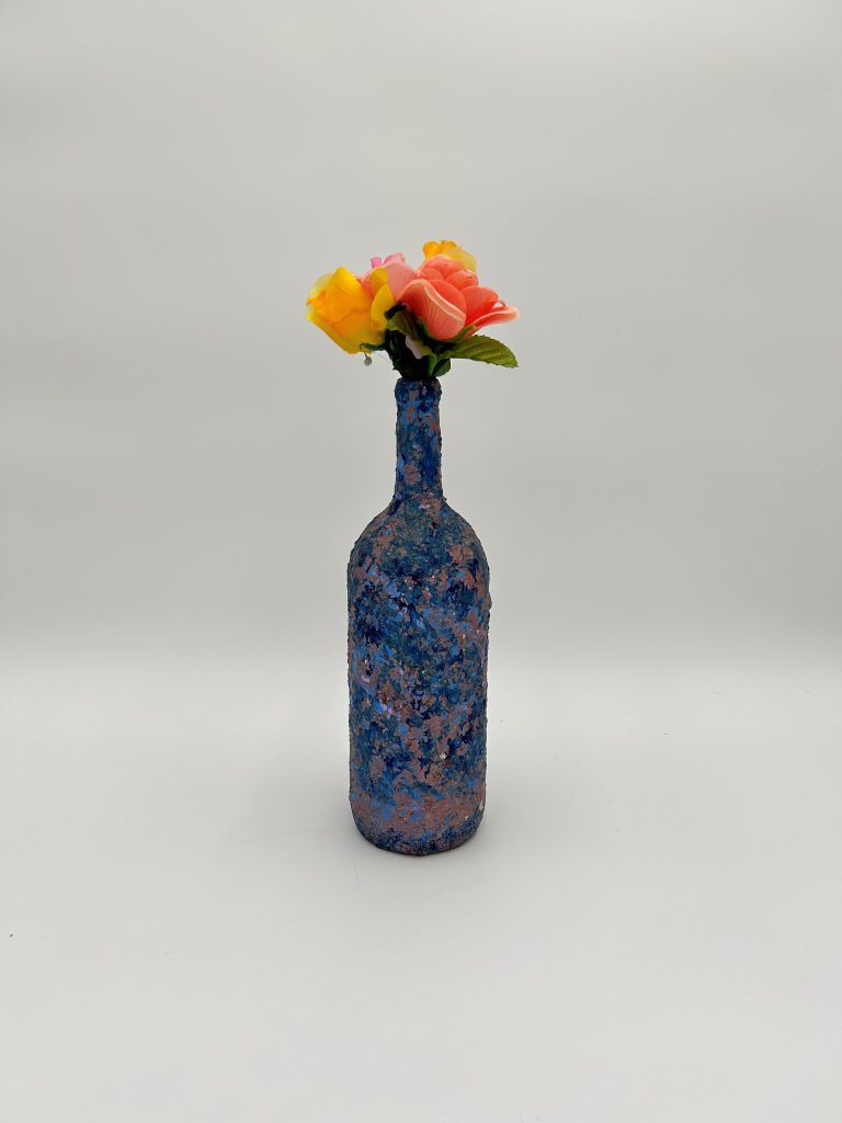 Hand painted blue swirl vase with yellow and peach flowers inside.