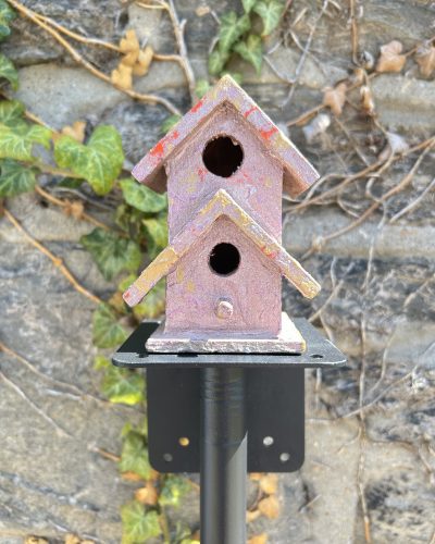 Hand painted dusty purple decorative birdhouse on pole outside