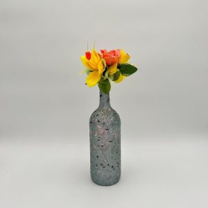 Teal blue painted glass vase with pink and black small spots, and colorful flowers inside.