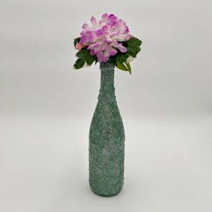 Pretty mint green vase with sage glitter and purple flower inside.