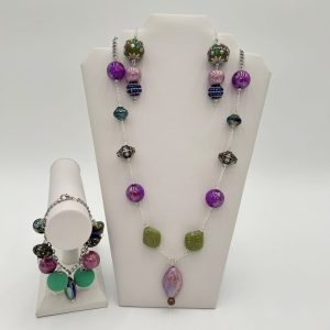 Purple beaded necklace with green and silver beads, along with earrings and bracelet.