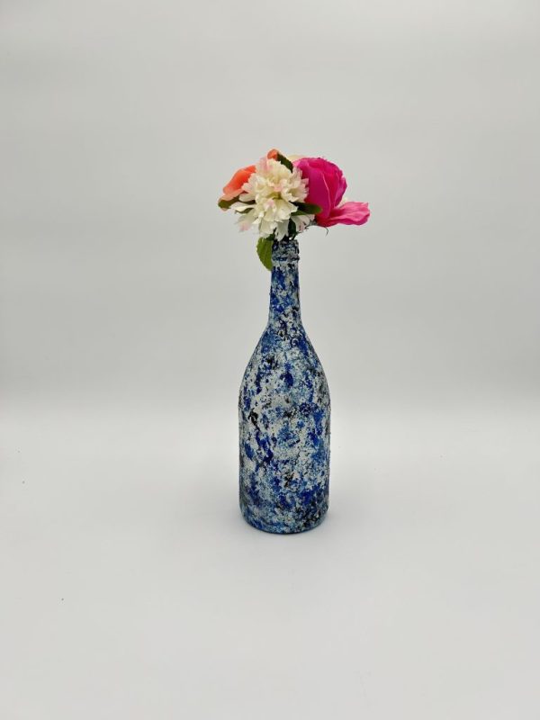 Royal blue unique glass vase with dashes of white and black, with pink and white flowers.