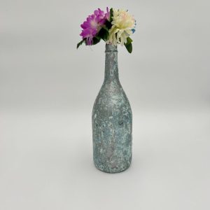 Glossy hand painted teal vase with bright flowers inside.