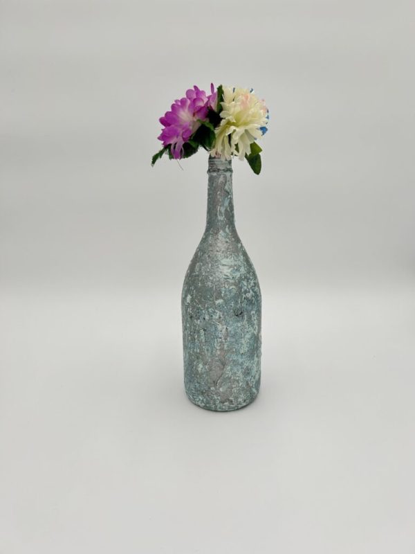 Glossy hand painted teal vase with bright flowers inside.