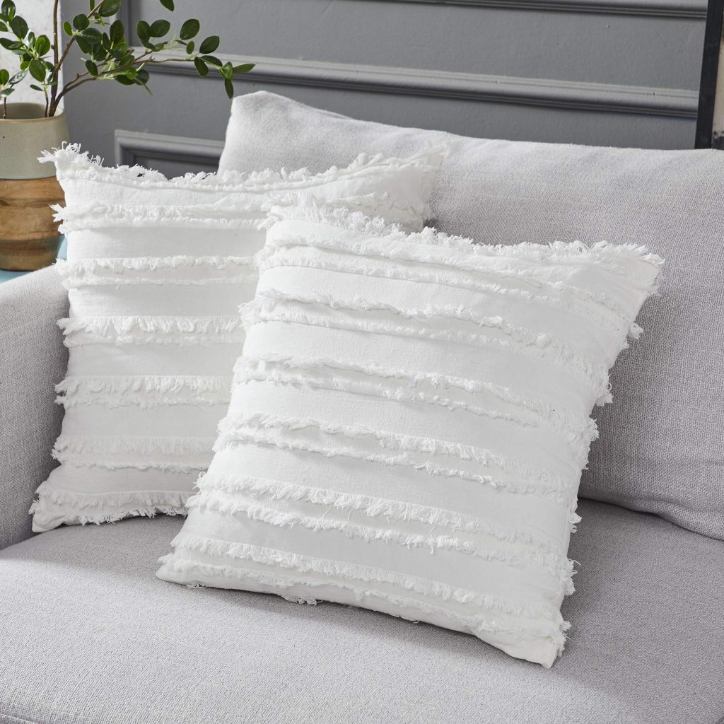 Two white decorative throw pillows sitting on sofa