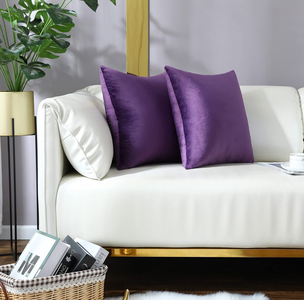 White sofa with beautiful purple throw pillows styled on it.