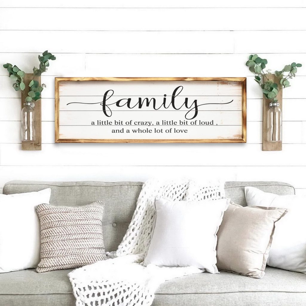 A gray and white interior home decor sign sitting above gray sofa and pillows.