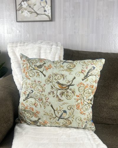 Large blue bird pillow sitting on brown sofa for nature theme decorating