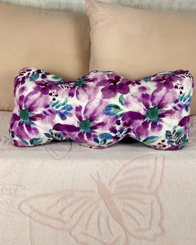 Handmade purple pillow with floral pattern sitting on pink bed