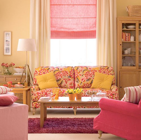 Peach color living room with yellow throw pillows and a pink sofa