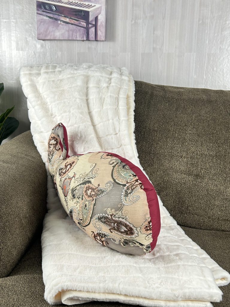 Paisley shaped red couch pillow sitting on brown sofa