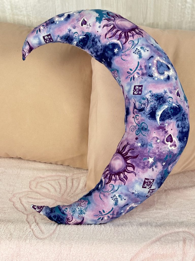 Blue and purple crescent moon pillow sitting on pink bed for fantasy theme decorating