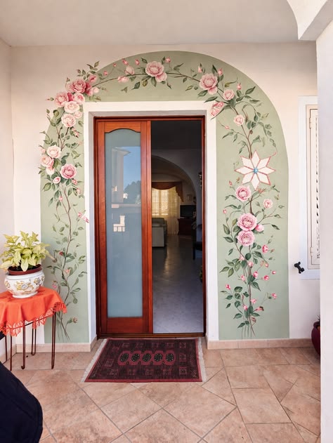 Hand painted pale green arch with floral pattern over doorway